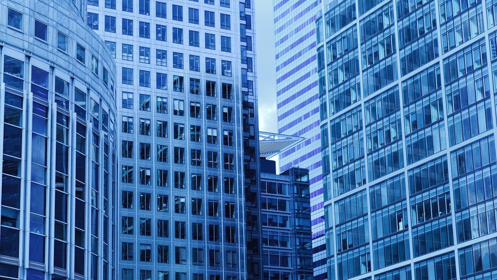 Blue tinted view of tall glass office buildings