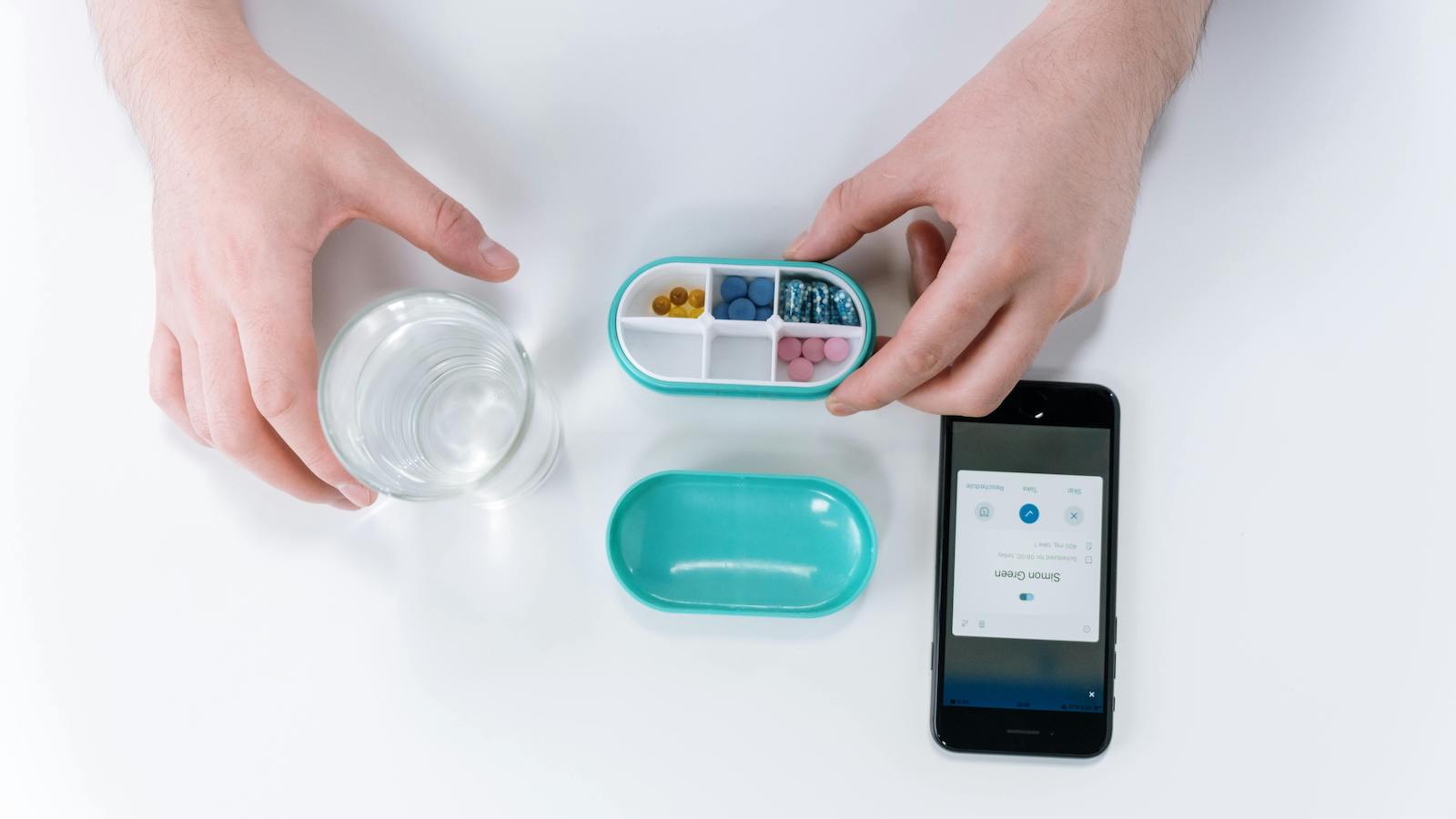 Person Holding Pill Box with Glass of Water and Phone