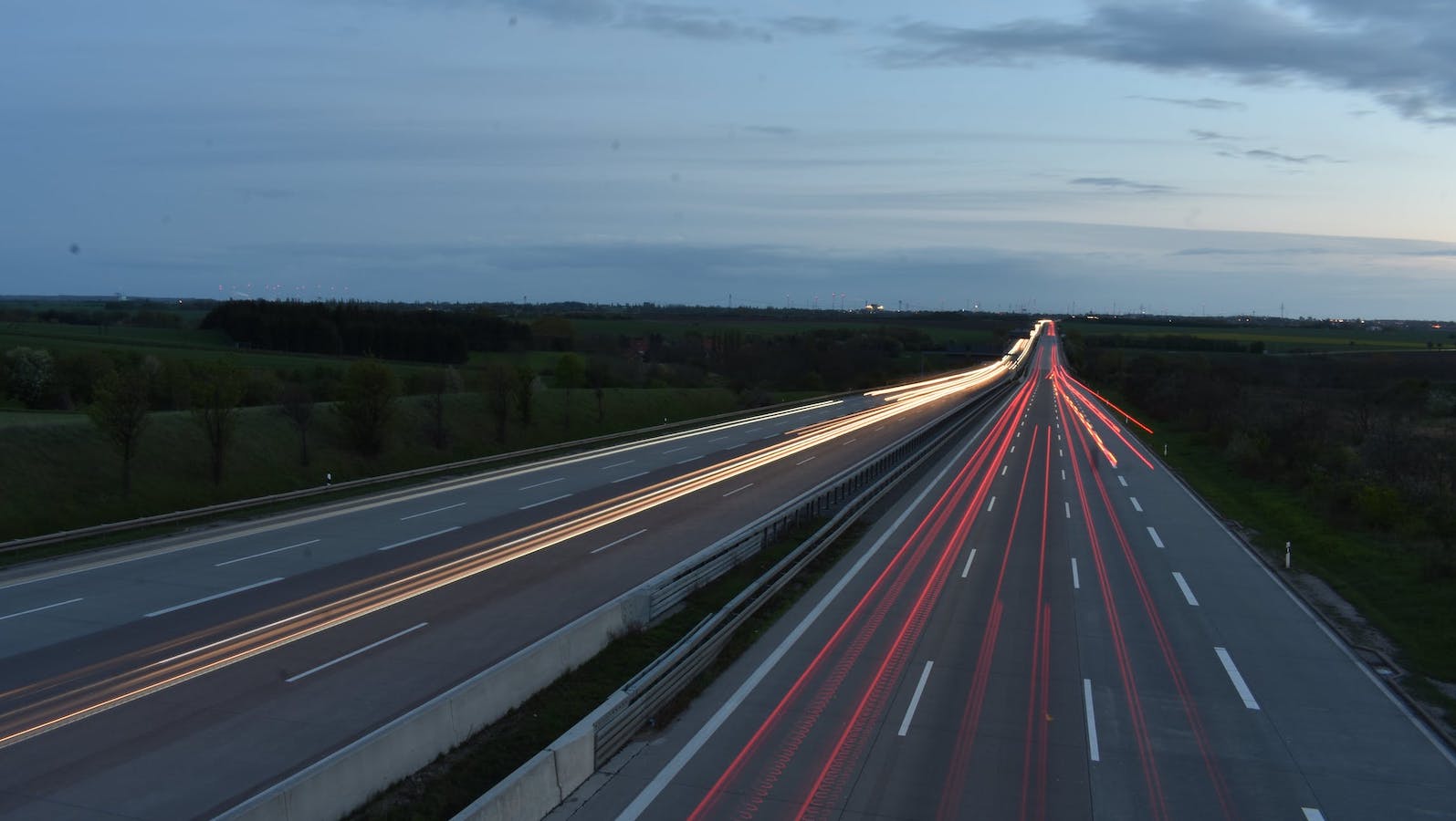 Time lapse photo of a freeway at dusk with red and white lights