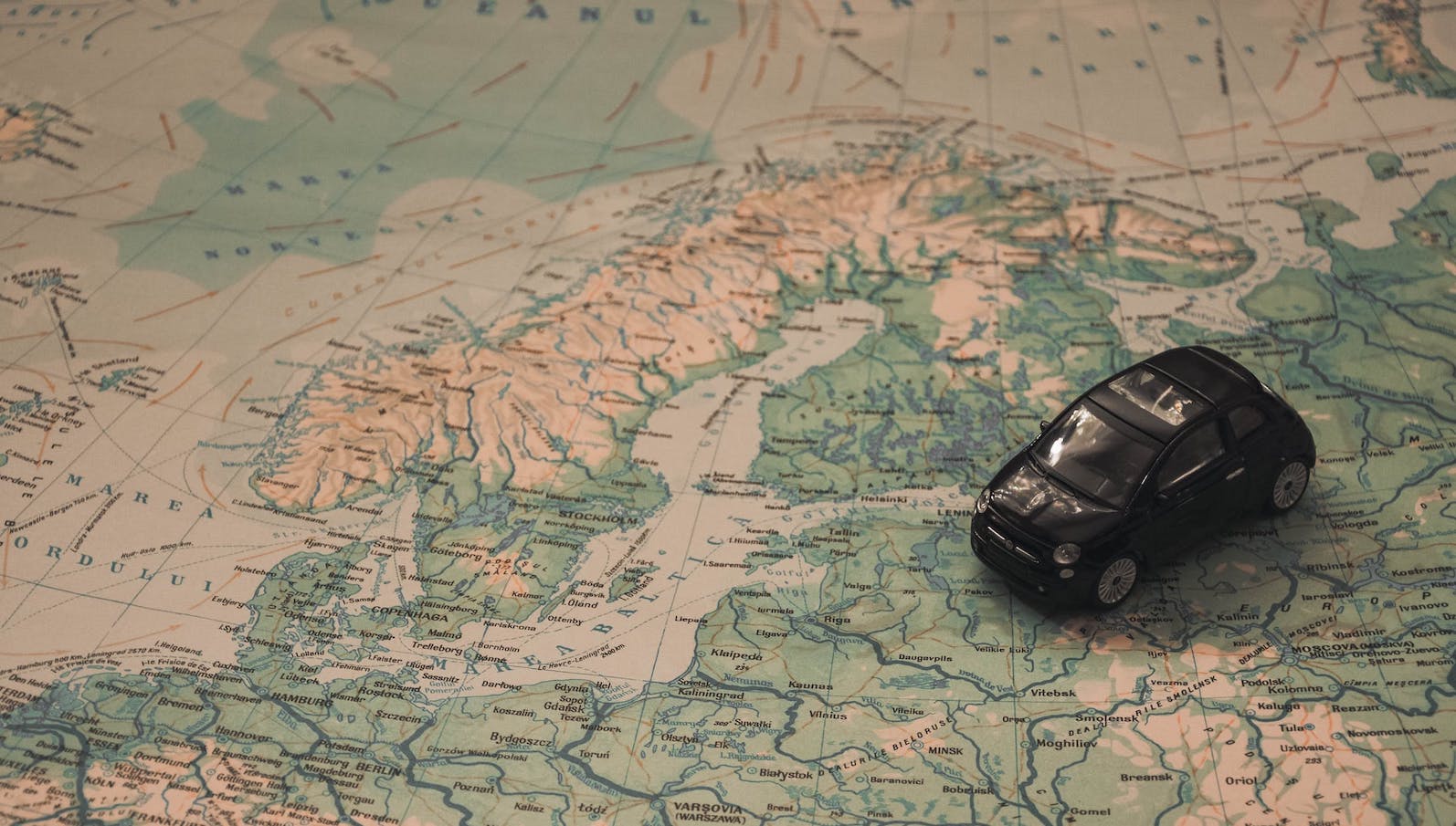 Black toy car atop a map of the world zoomed in