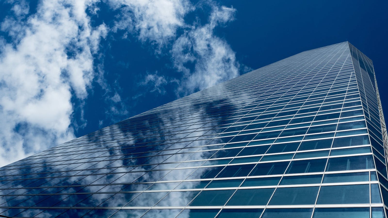Low angle image of tall glass office buildings against a bright and cloudy sky