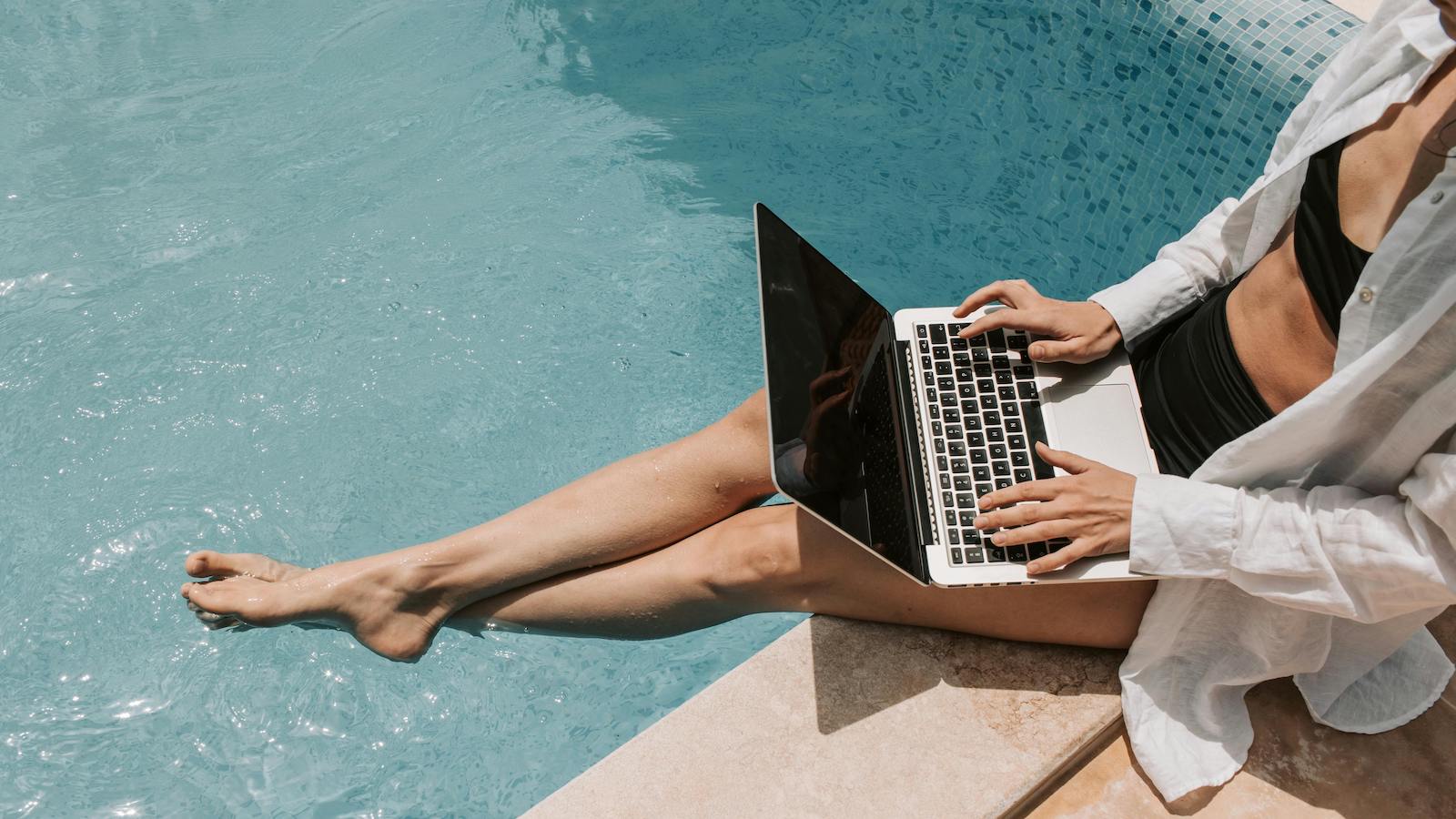Woman Sitting on Poolside Using Laptop