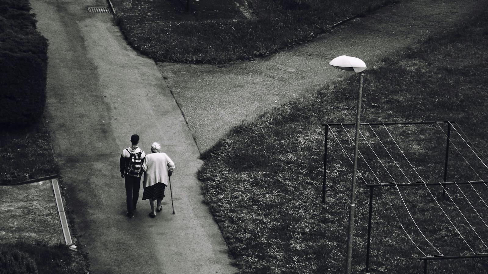 Man Walking Beside Older Woman on Road