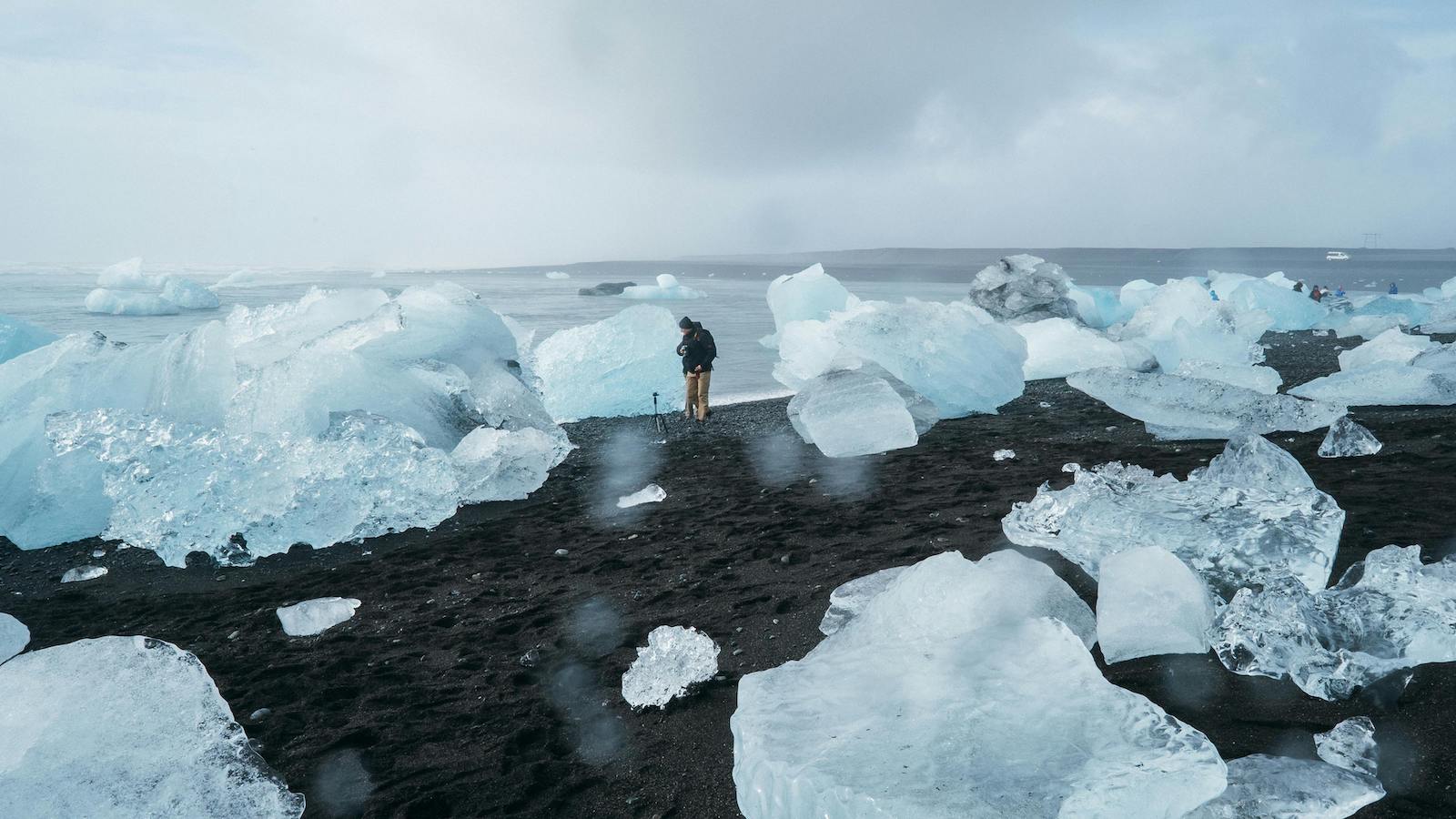 Person standing beside body of water among chunks of ice