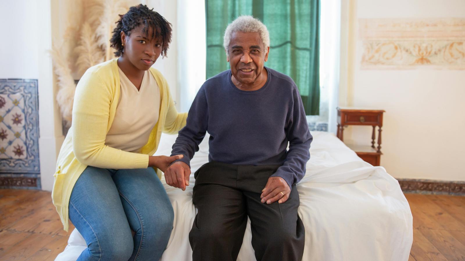 Woman and Elderly Man Sitting on Bed