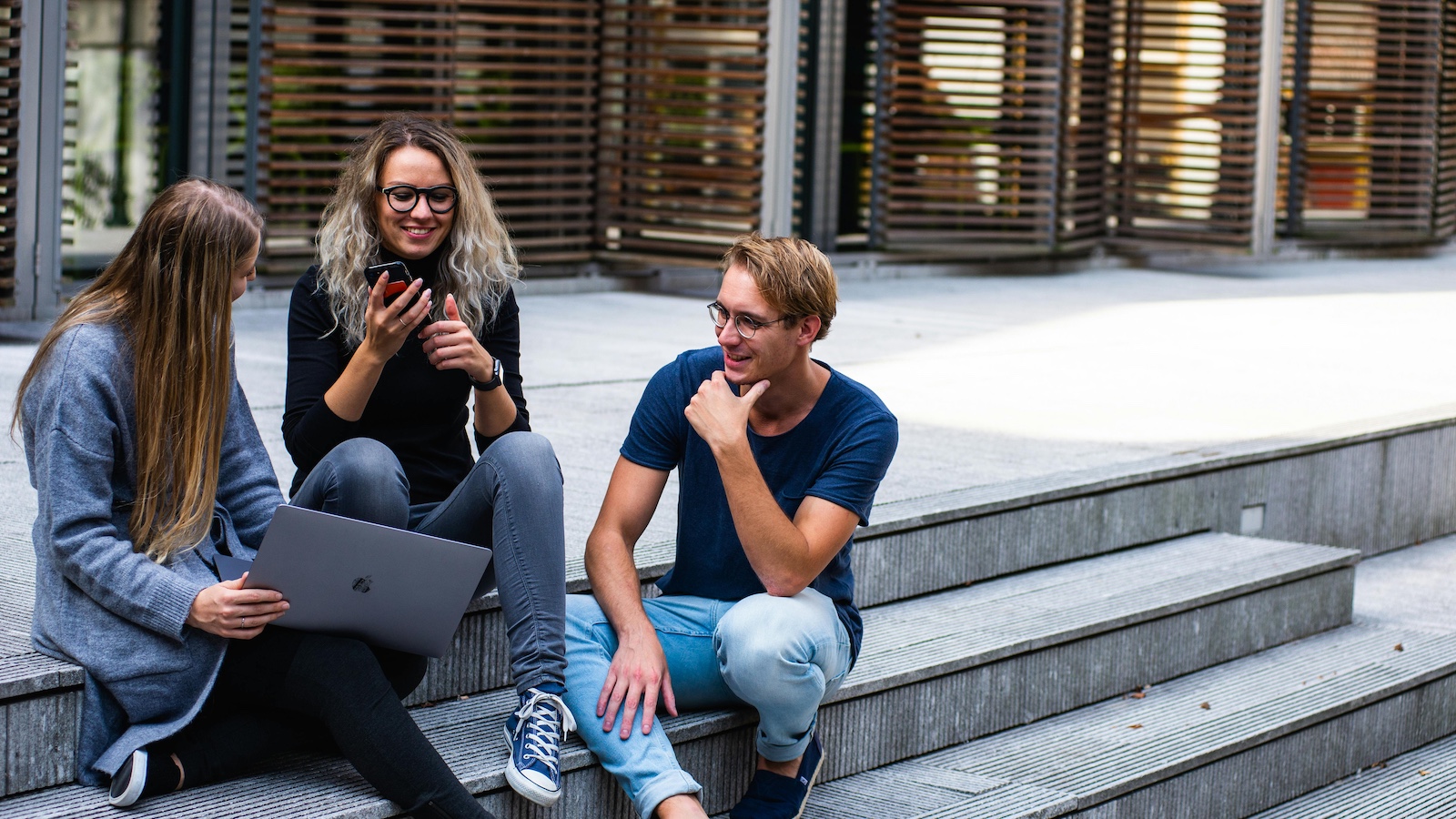 Three Young People Sitting on the Stairs Talking With Each Other