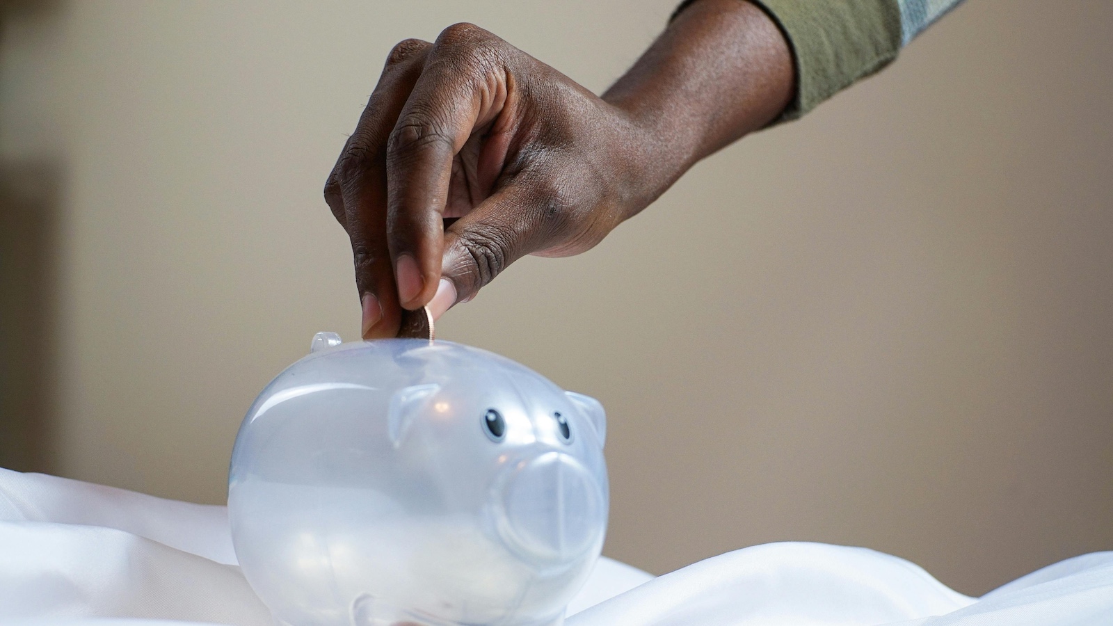 Person Putting Coin in a Piggy Bank